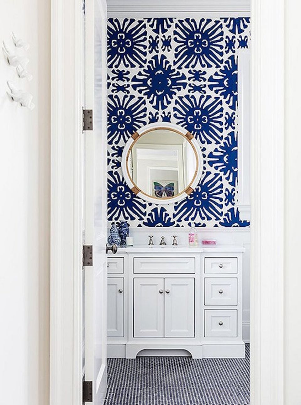 Bold blue and white geometric star wallpaper in powder room with white vanity and round mirror for striking focal point.