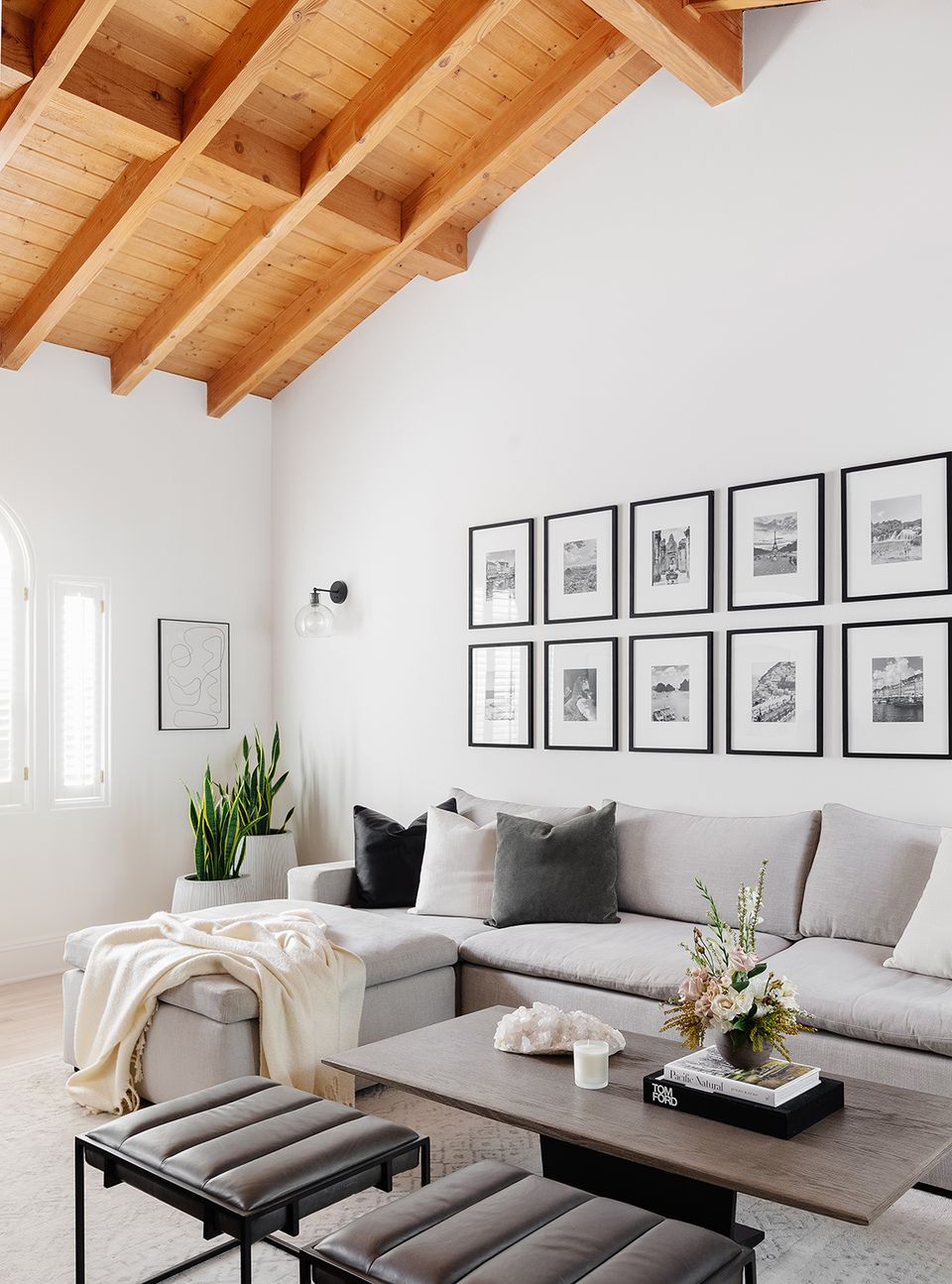 Modern farmhouse with exposed wood beams, gallery wall grid, and soft gray upholstery