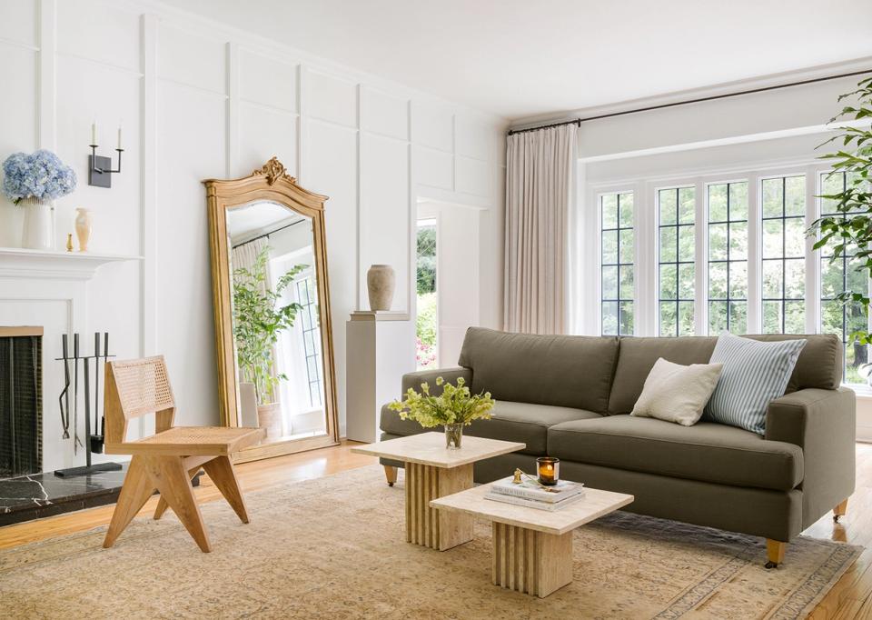 Bright minimalist living room with sage green sofa, natural wood accents, and neutral palette