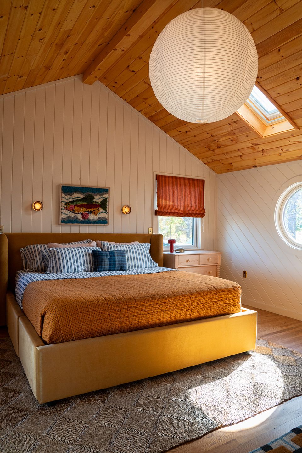 Modern cabin bedroom with warm wood ceiling, golden-yellow bed frame, and natural light
