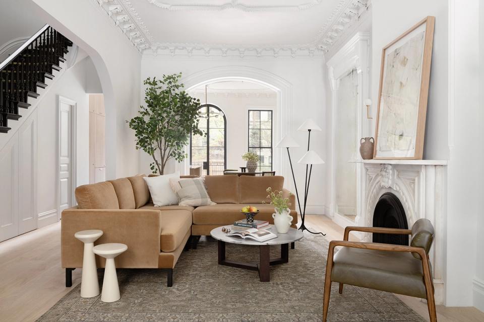 Minimalist cream living room with camel sectional, fireplace, and bright airy aesthetic