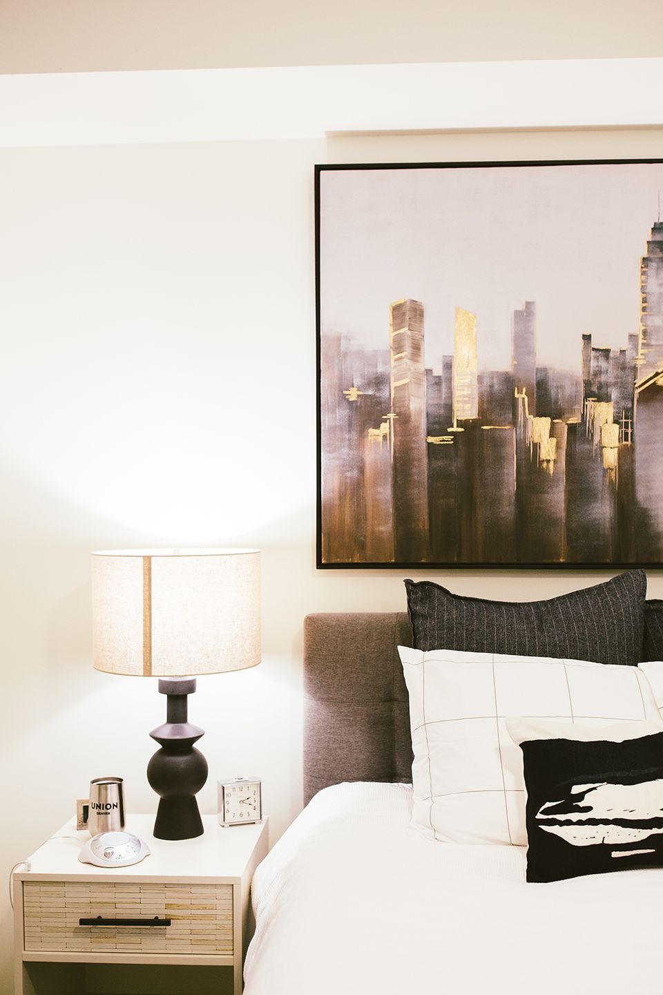Modern boho with charcoal headboard, cityscape art, warm wood nightstand, and monochrome accents