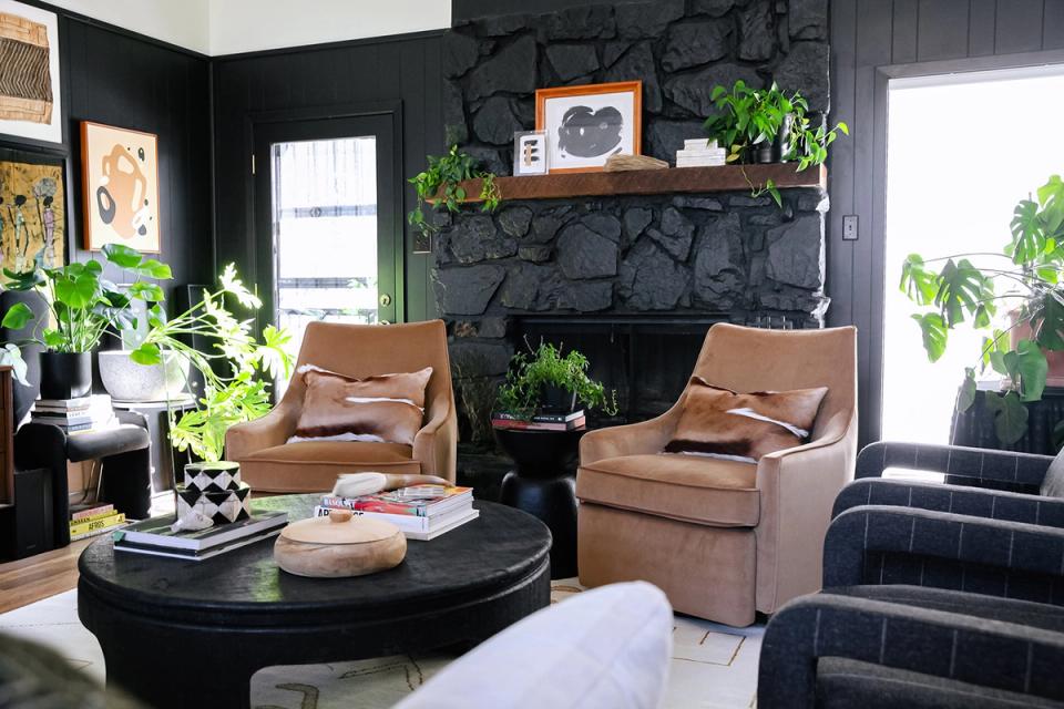 Eclectic dark fireplace wall with cognac seating, lush greenery, and moody atmosphere