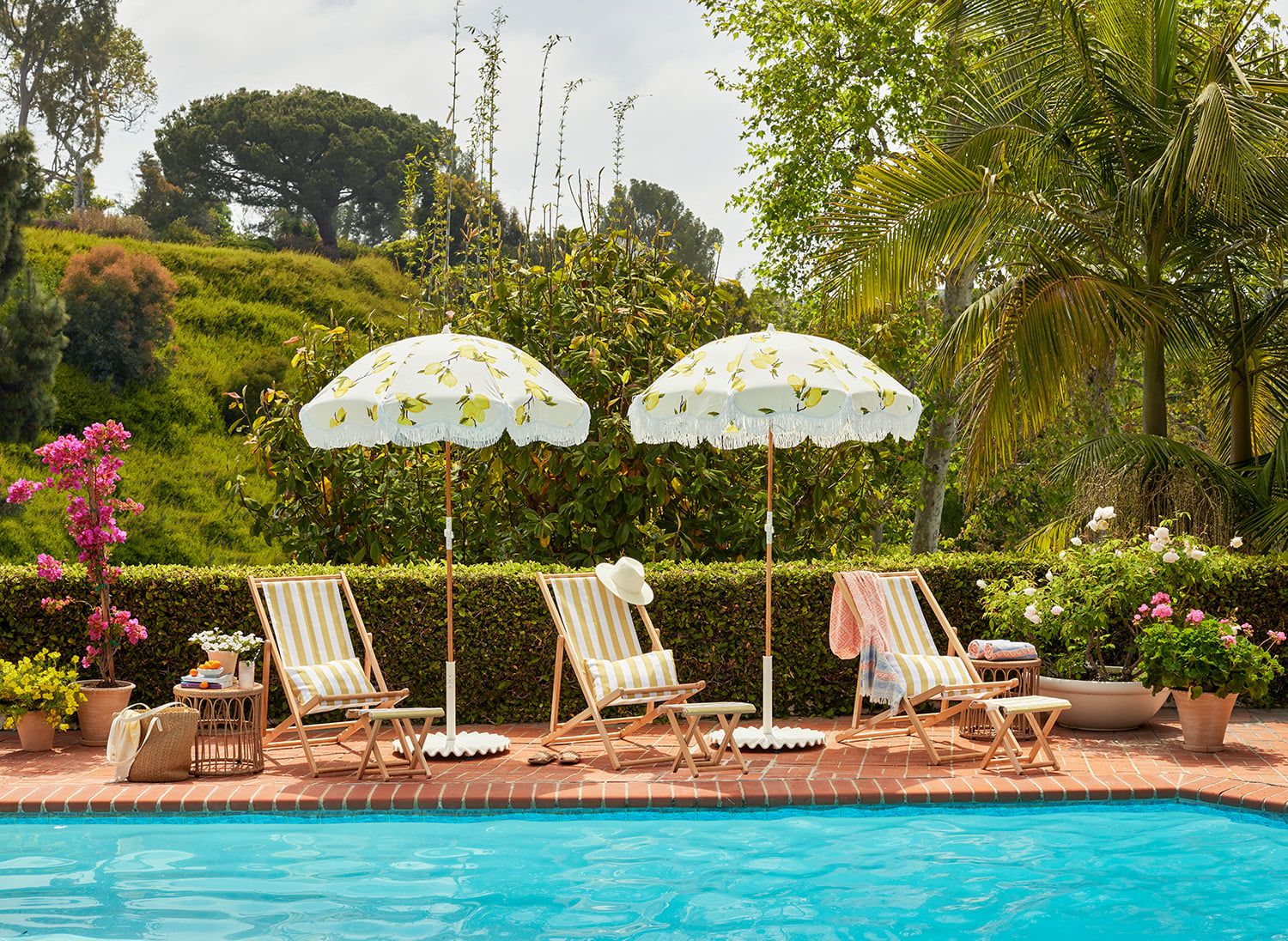 Retro 1960s poolside retreat with striped loungers, patterned umbrellas, lush landscaping