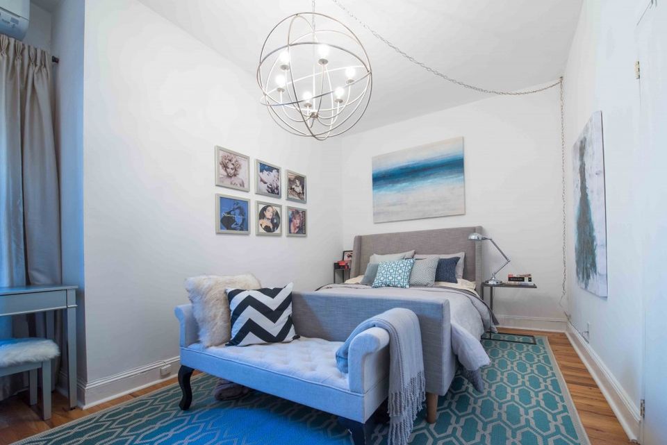 Modern bedroom with geometric accent wall, blue lighting, and contemporary pendant fixture