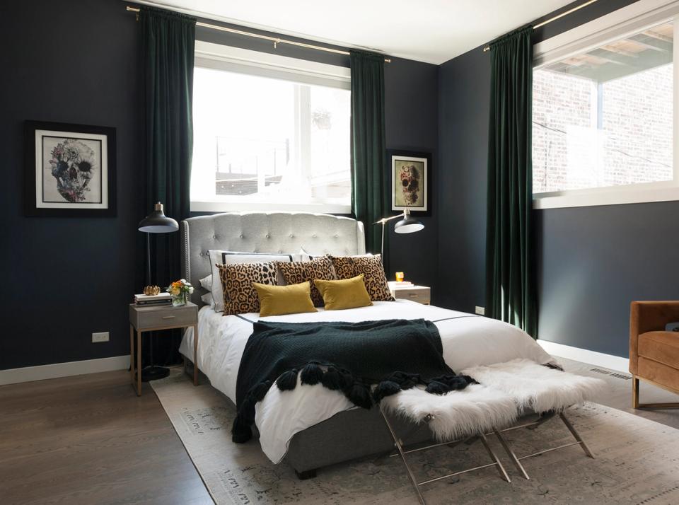 Dramatic dark green bedroom with gold pillows, floor-to-ceiling curtains, and moody sophisticated ambiance