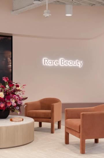 Minimalist lounge with cognac chairs, cream circular table, and glowing brand signage