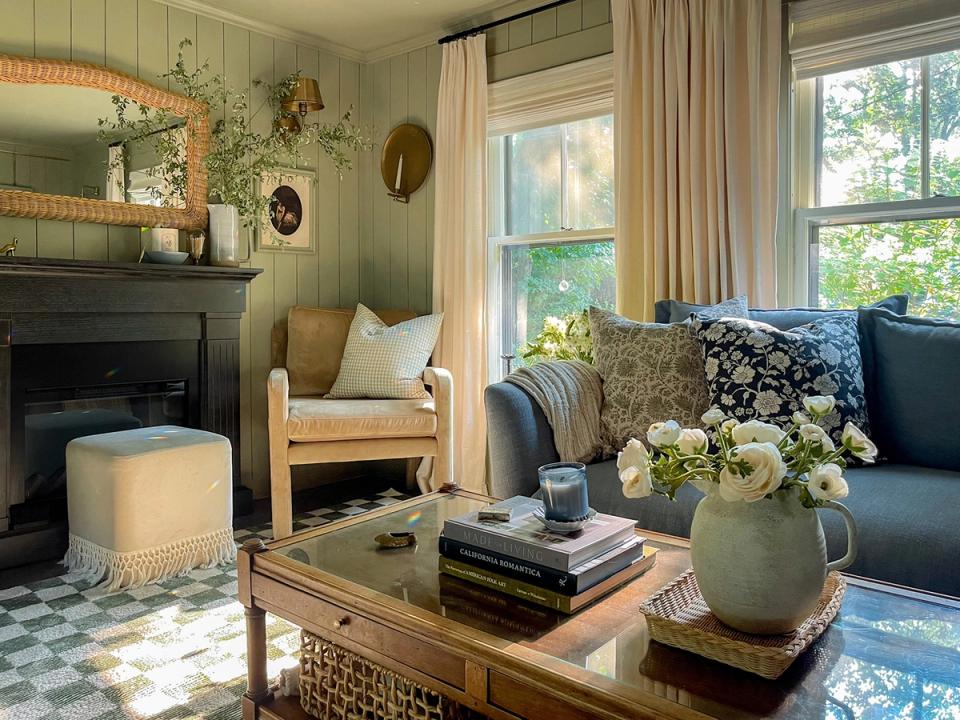 Refined green parlor with navy seating, natural wood details, and classic botanical arrangements