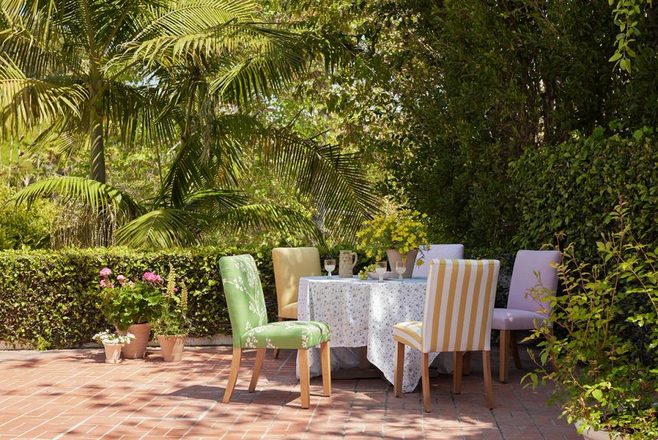 Tropical dining setup with verdant canopy, colorful upholstered chairs, and warm terracotta flooring evoking lush paradise.