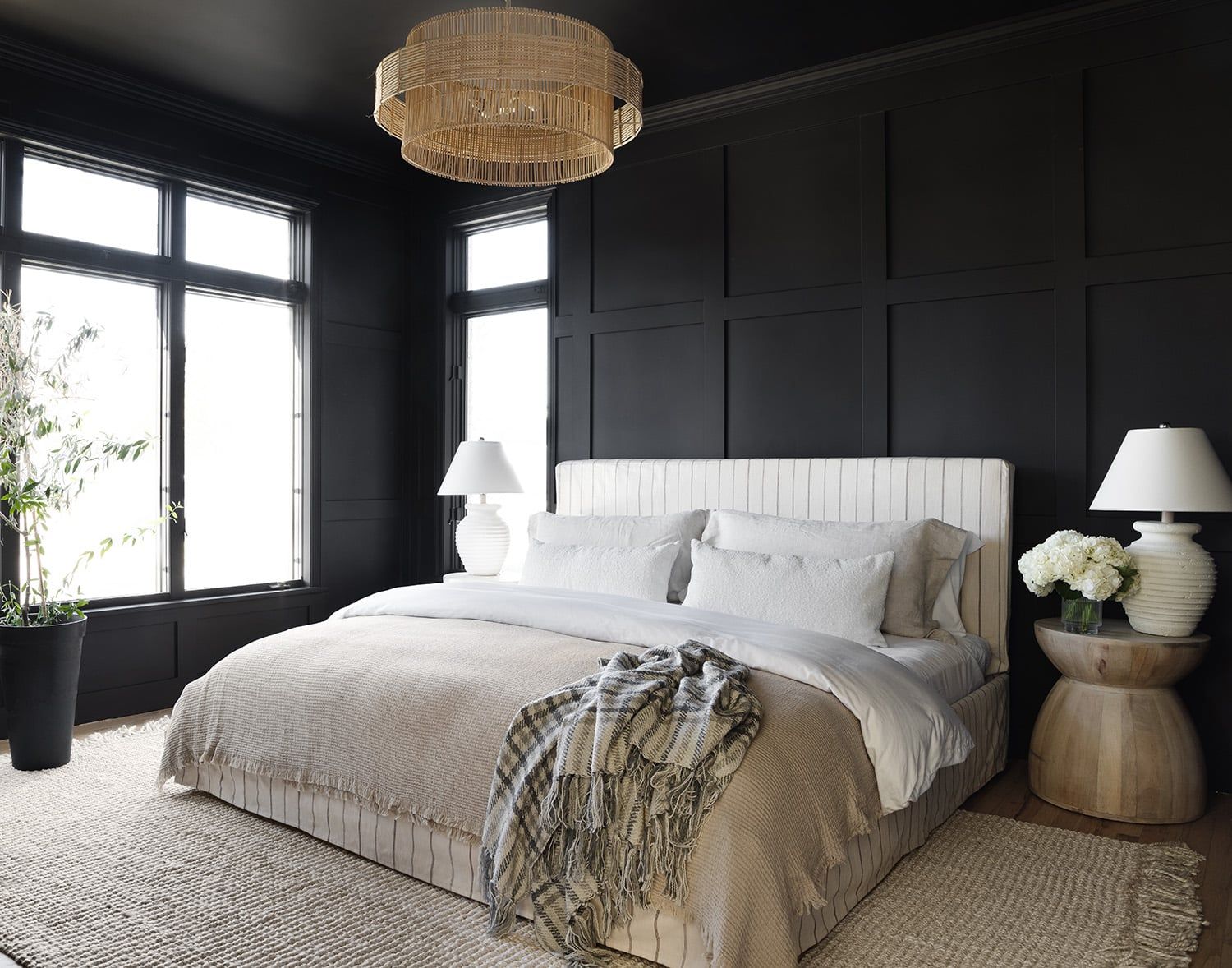 Modern bedroom with dark paneled walls, white bedding, and brass pendant light creating moody sophistication