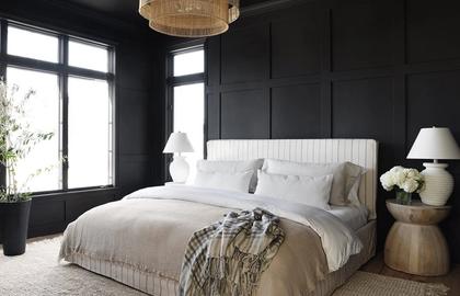 Modern bedroom with dark paneled walls, white bedding, and brass pendant light creating moody sophistication