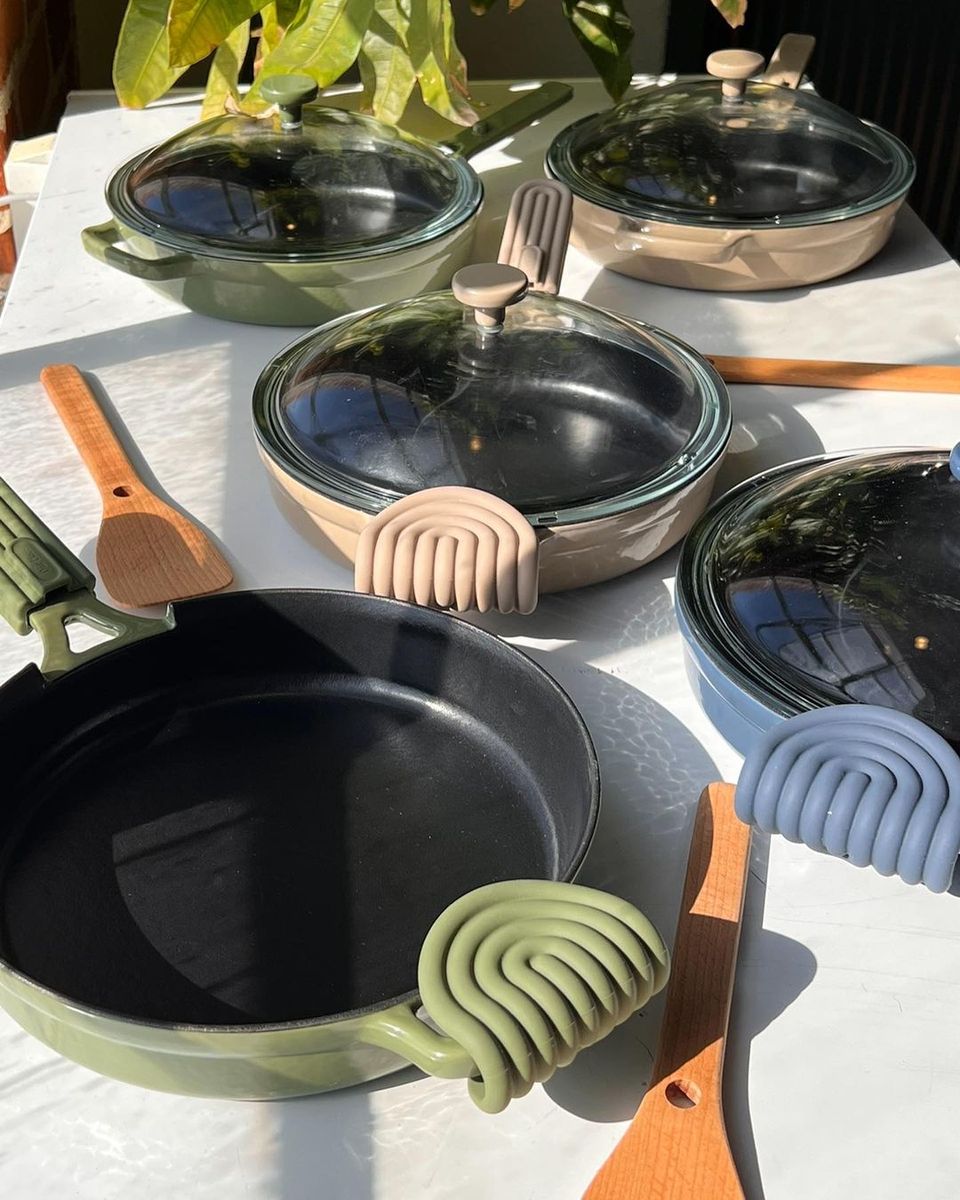 Eco-friendly cookware collection featuring black and green pans with natural wood handles displayed