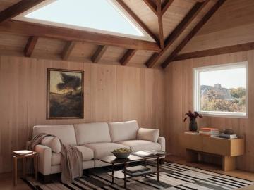 Warm mid-century modern cabin retreat with taupe sofa, exposed wood beams, and skylight
