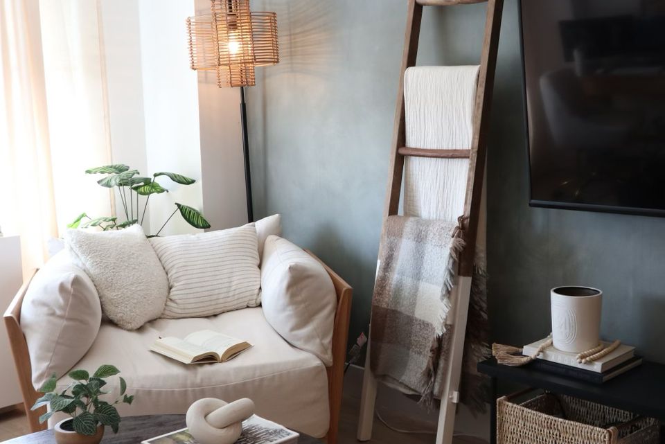 Serene bedroom nook with sage green limewash accent wall, cream bedding, and warm wood frame.