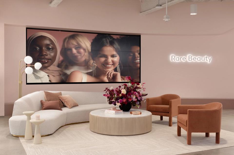 Luxe lounge with curved cream sofa, cognac chairs, and editorial brand imagery on wall