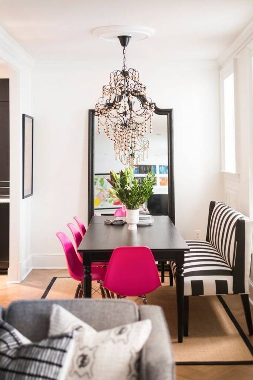 Modern dining nook with hot pink chairs, crystal chandelier, and black-and-white striped accents