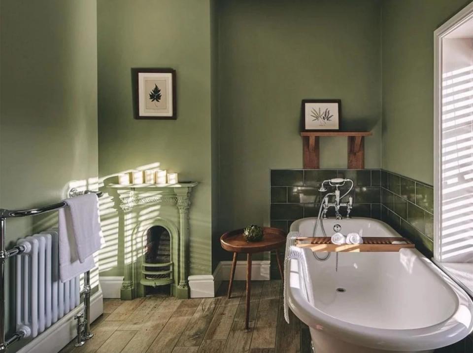 Vintage-inspired bathroom in muted sage green with freestanding tub, brass fixtures, and traditional heritage elements evoking timeless elegance