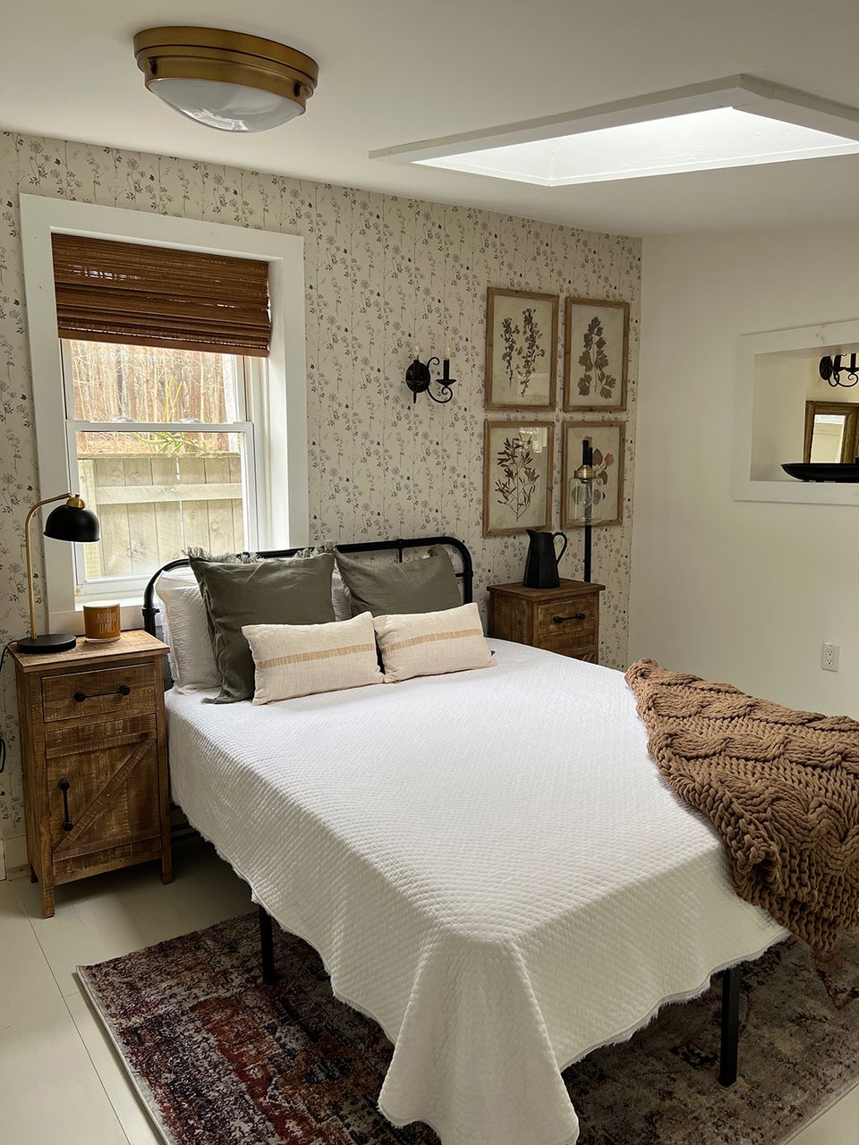 Cozy farmhouse bedroom with floral wallpaper, vintage wood furniture, and botanical prints