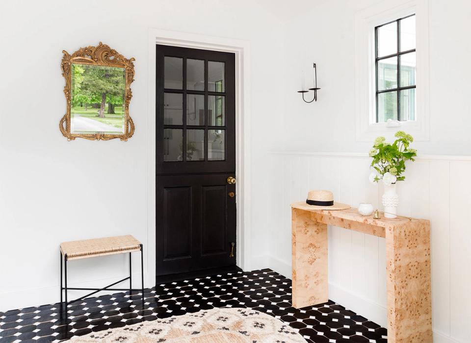 Scandinavian entryway with black-and-white geometric flooring, cork console, and ornate mirror