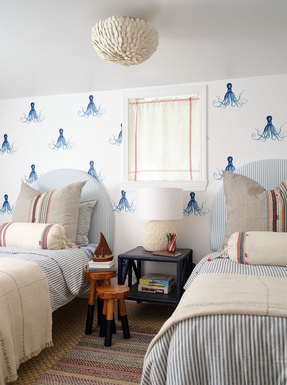 Coastal bedroom with blue nautical wallpaper, striped bedding, and serene white backdrop