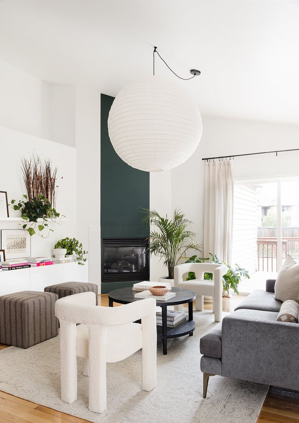 Modern living room with dark fireplace accent, sculptural white furnishings, and minimalist greenery styling