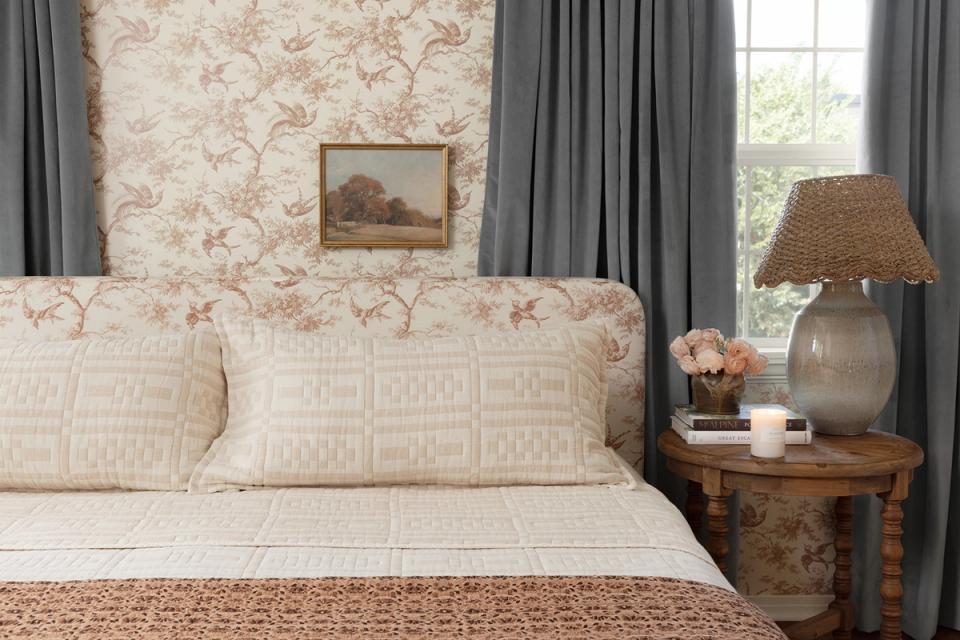 Traditional feminine bedroom with floral toile wallpaper, gray drapes, and layered textures