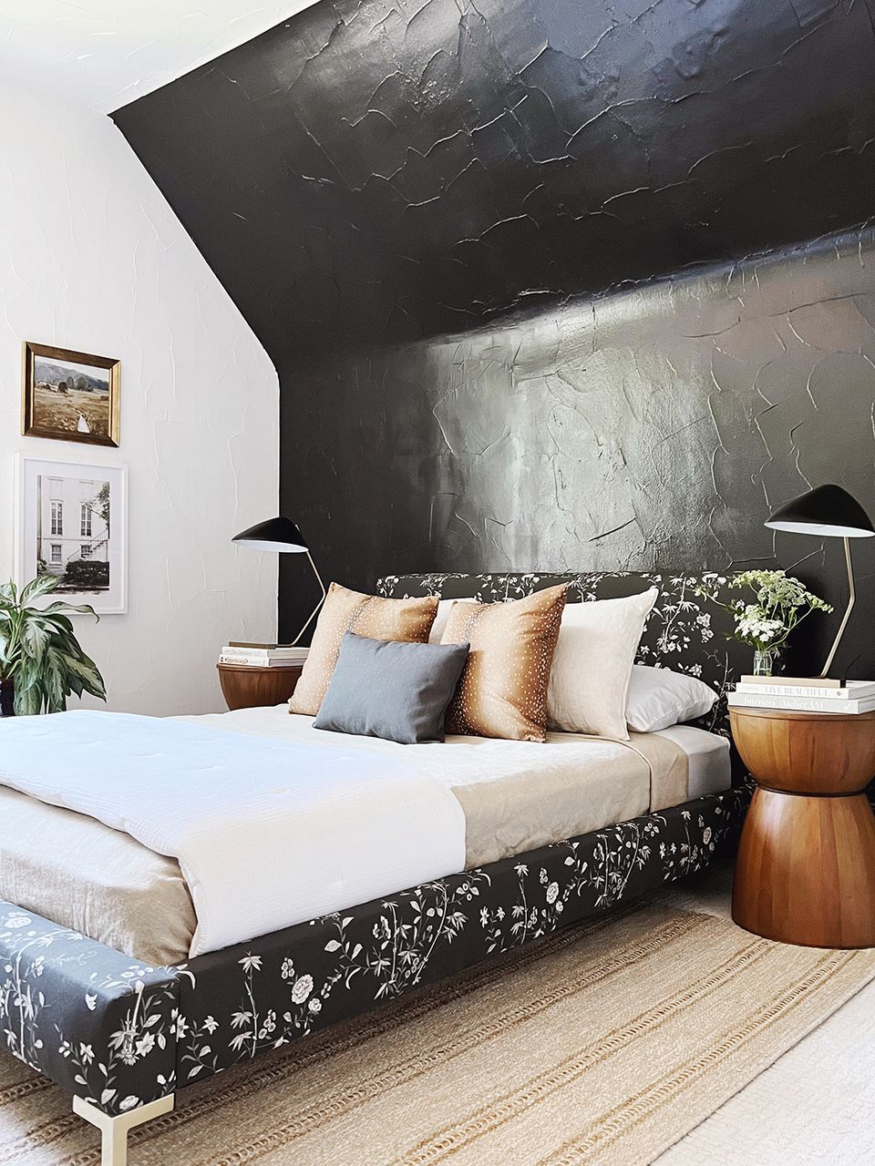 Modern bedroom with bold black textured accent wall, neutral bedding with warm tones, and natural wood side tables
