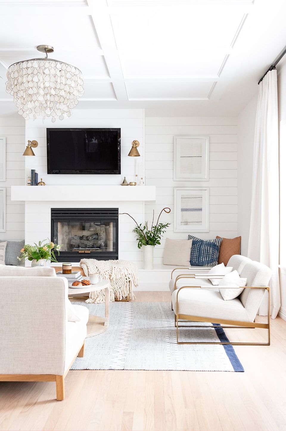 Luxury modern living room with crisp white paneling, crystal chandelier, fireplace, and neutral tones creating serene, elegant sanctuary