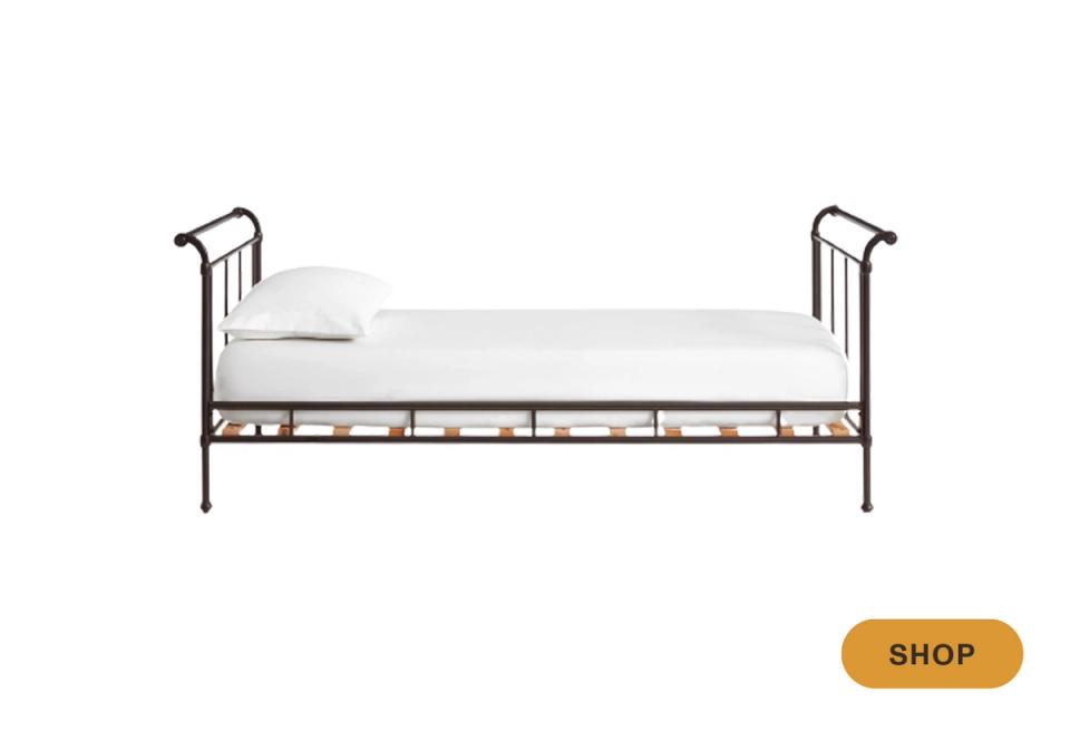 Industrial metal daybed with scrolled headboard and cream bedding