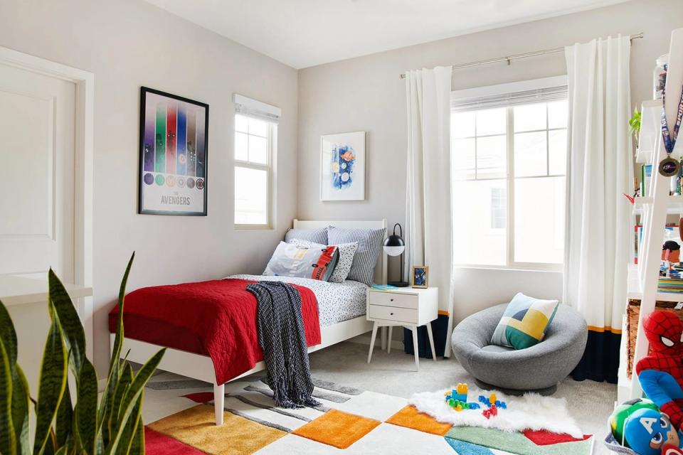 Modern minimalist bedroom blending clean lines with playful pops of red, colorful geometric area rug, and bright natural light for energetic yet organized space.