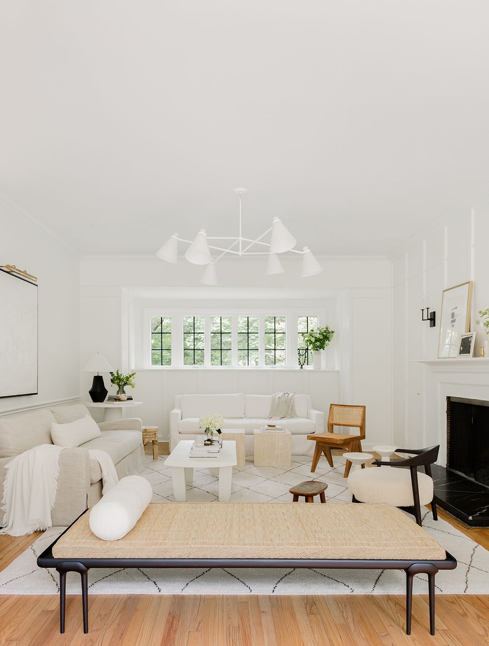 Minimalist white bedroom with airy layout, fireplace, and warm wood flooring creating serene atmosphere