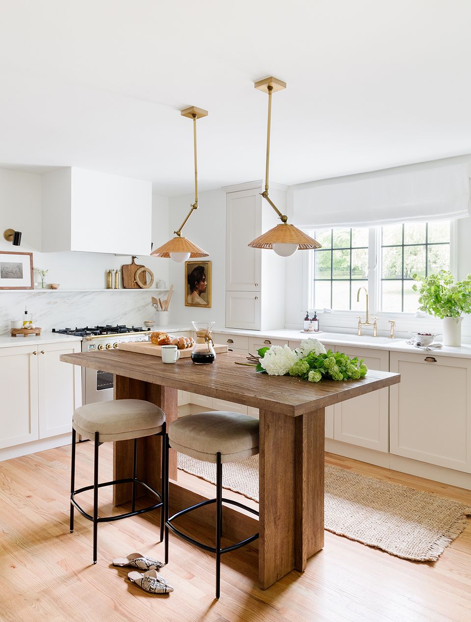 Farmhouse kitchen with warm wood island, brass pendant lights, natural materials, and bright airy aesthetic