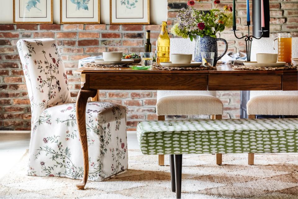 Eclectic dining space with floral chair, botanical prints, and green patterned bench