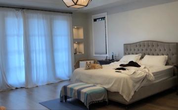 Sophisticated bedroom with blue sheer curtains, gray upholstered headboard, and geometric pendant lighting