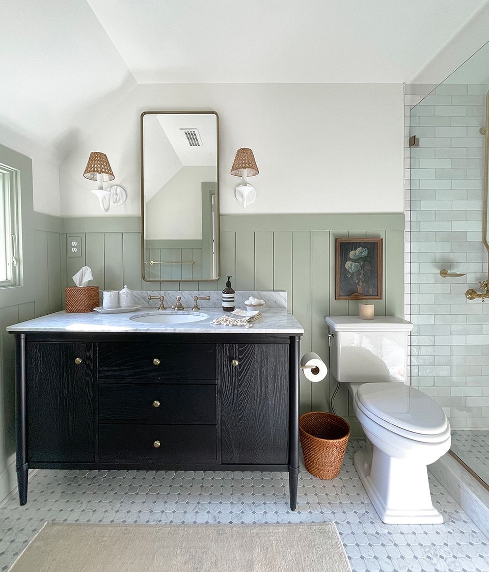 Serene cottage bathroom featuring sage paneling, crisp white subway tile, black vanity, and natural light