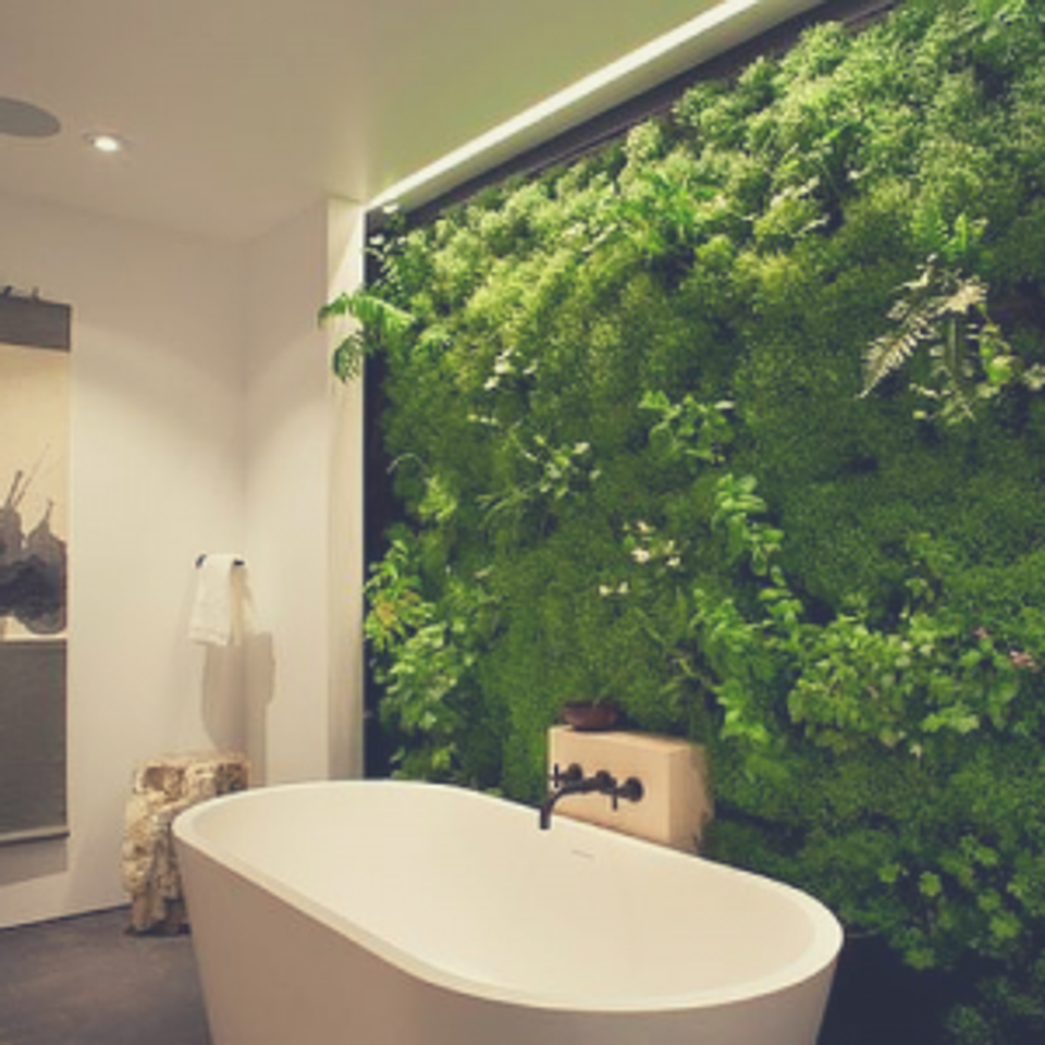 Luxe spa bathroom with living green wall backdrop and freestanding white soaking tub