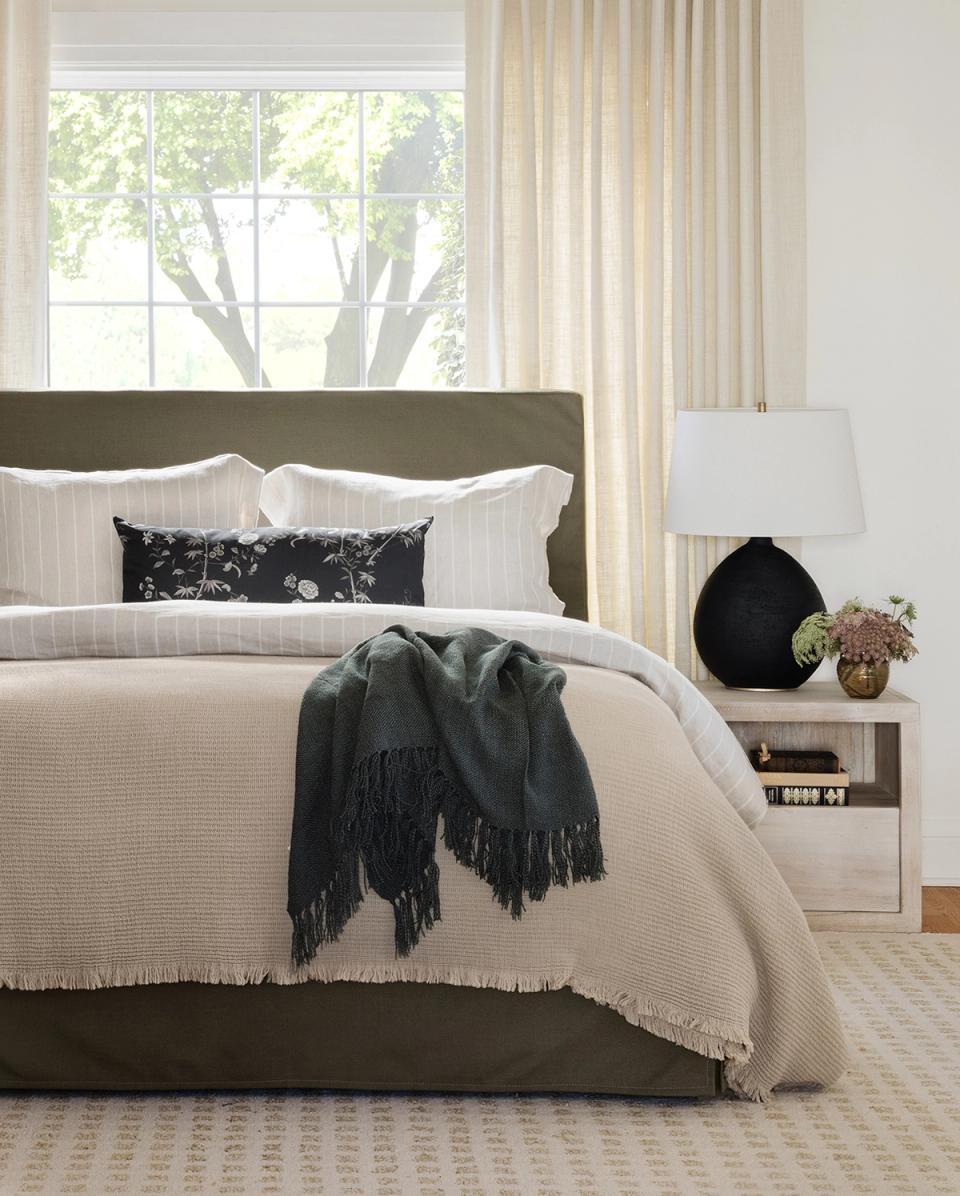 Serene modern bedroom with sage green upholstered headboard, cream waffle-weave bedding, and monochromatic accents creating a calming, contemporary retreat