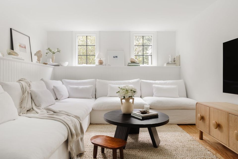 Serene Scandinavian living room with neutral palette, cream sectional, layered throw blankets, and warm wood accents