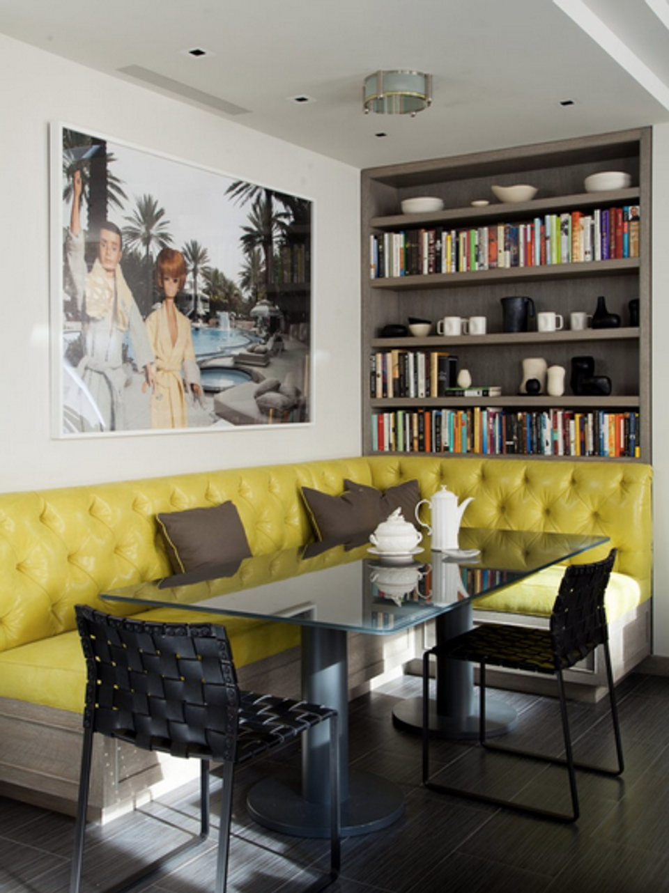 Modern dining nook with chartreuse tufted banquette, black chairs, and curated bookshelf backdrop