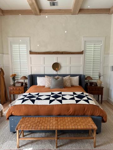 Farmhouse bedroom with white shiplap accent wall, geometric quilt, and warm wood furnishings