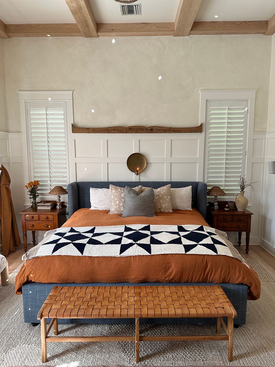 Farmhouse bedroom with white shiplap accent wall, geometric quilt, and warm wood furnishings