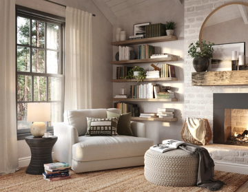 Serene reading nook with cream curved chair, floating shelves, fireplace, and natural light from large windows