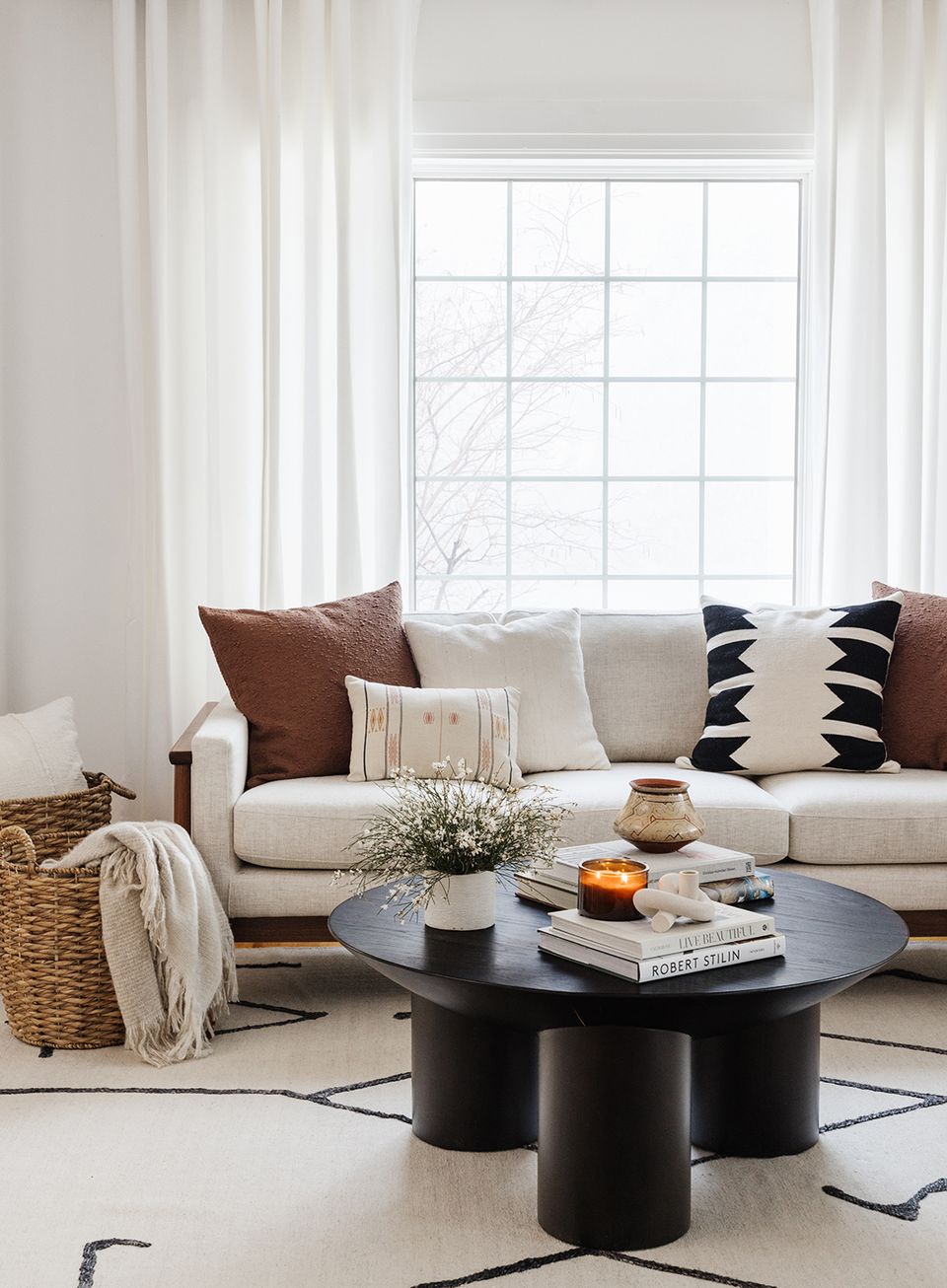 Modern living room with neutral palette, geometric pillows, and sculptural black coffee table
