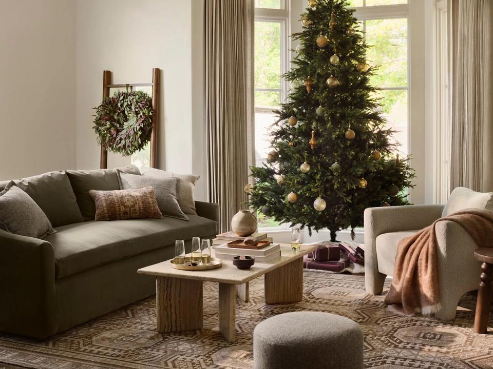 Warm traditional living room with olive green sofa, natural wood accents, and decorated Christmas tree