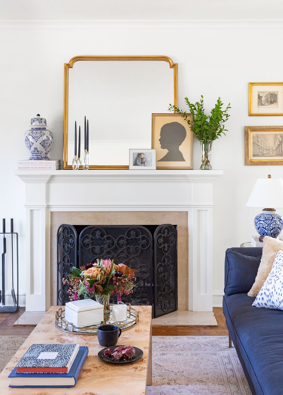 Classic Victorian room with white mantel, blue accents, decorative fireplace screen, and gold mirror