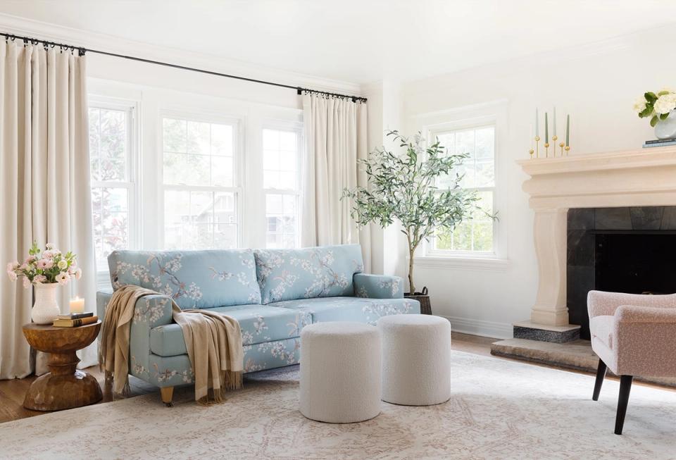 Coastal-inspired living room with light blue patterned sofa, cream drapery, minimalist white coffee table, and serene color palette