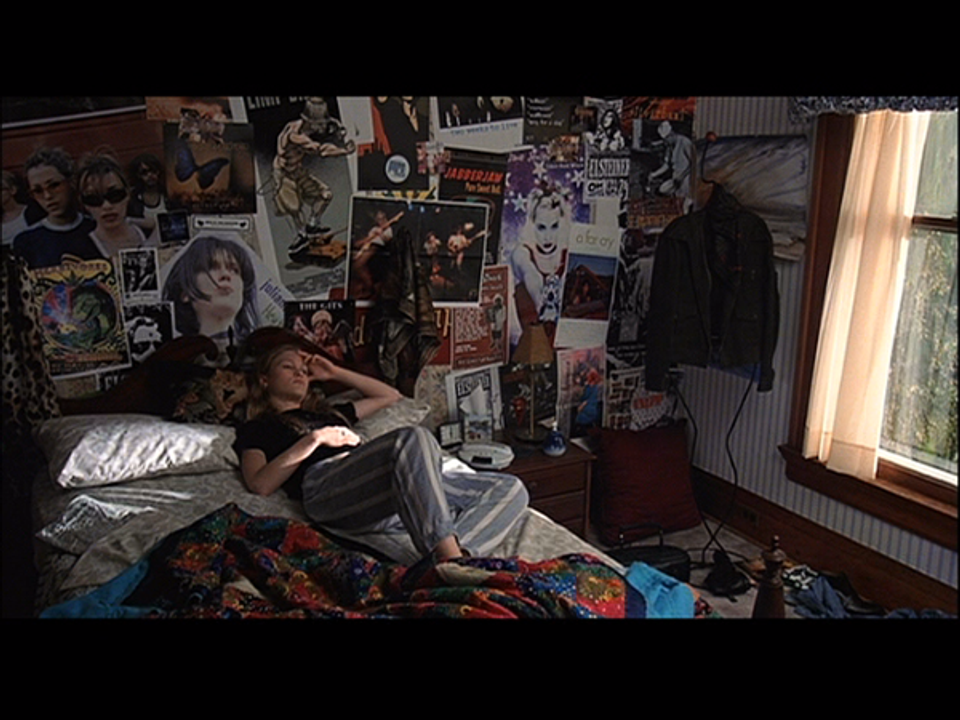 Moody dark bedroom with eclectic poster collage wall and intimate warm lighting