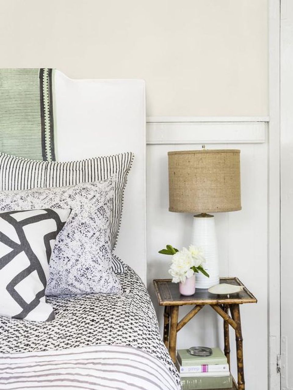 Scandinavian bedroom corner with layered textiles, natural wood nightstand, and soft palette