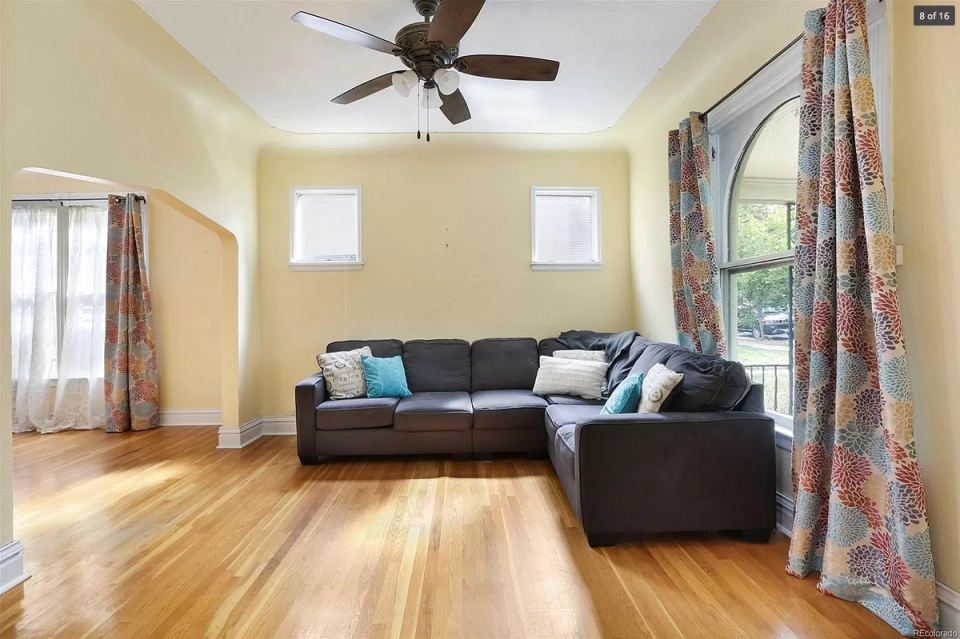 Bright, airy room with yellow walls, dark leather seating, and patterned curtains
