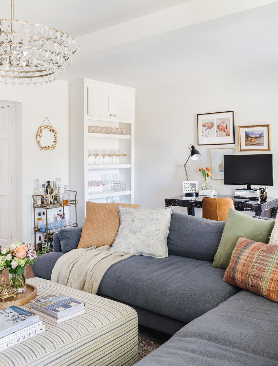 Contemporary bedroom mixing charcoal sofa with warm caramel accents, layered textures, and curated artwork